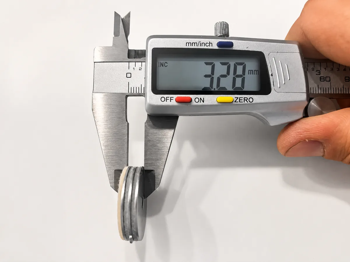Digitaler Messschieber misst die Gesamthöhe eines kompletten Bremsscheiben-Pakets aus Metall- und Filzscheiben: 7,28 mm